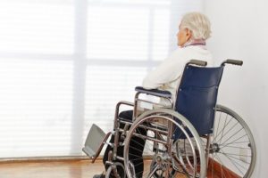 senior staring at window while sitting in wheel chair