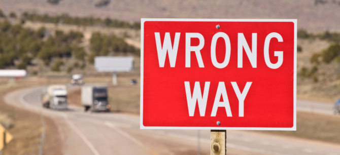 Wrong way sign to the side of a freeway off ramp.